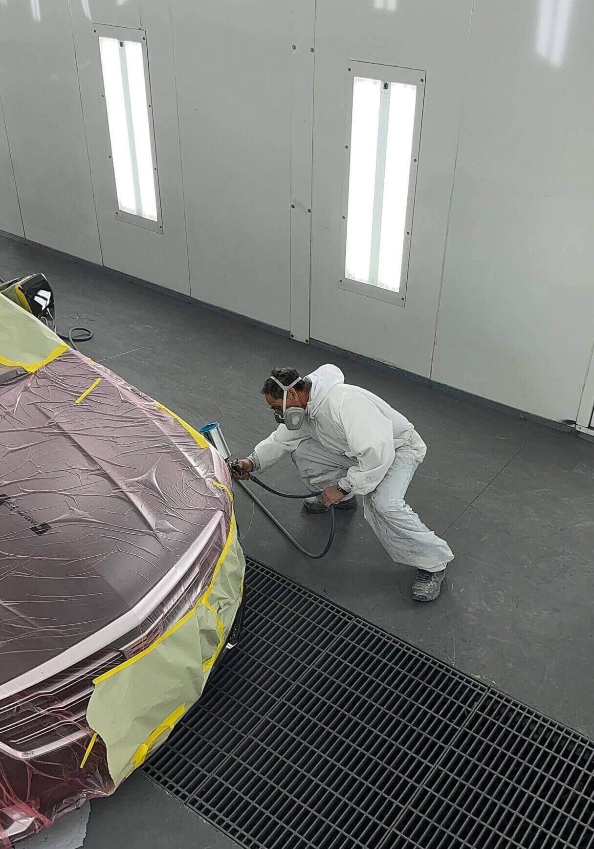 Person painting a car in workshop.