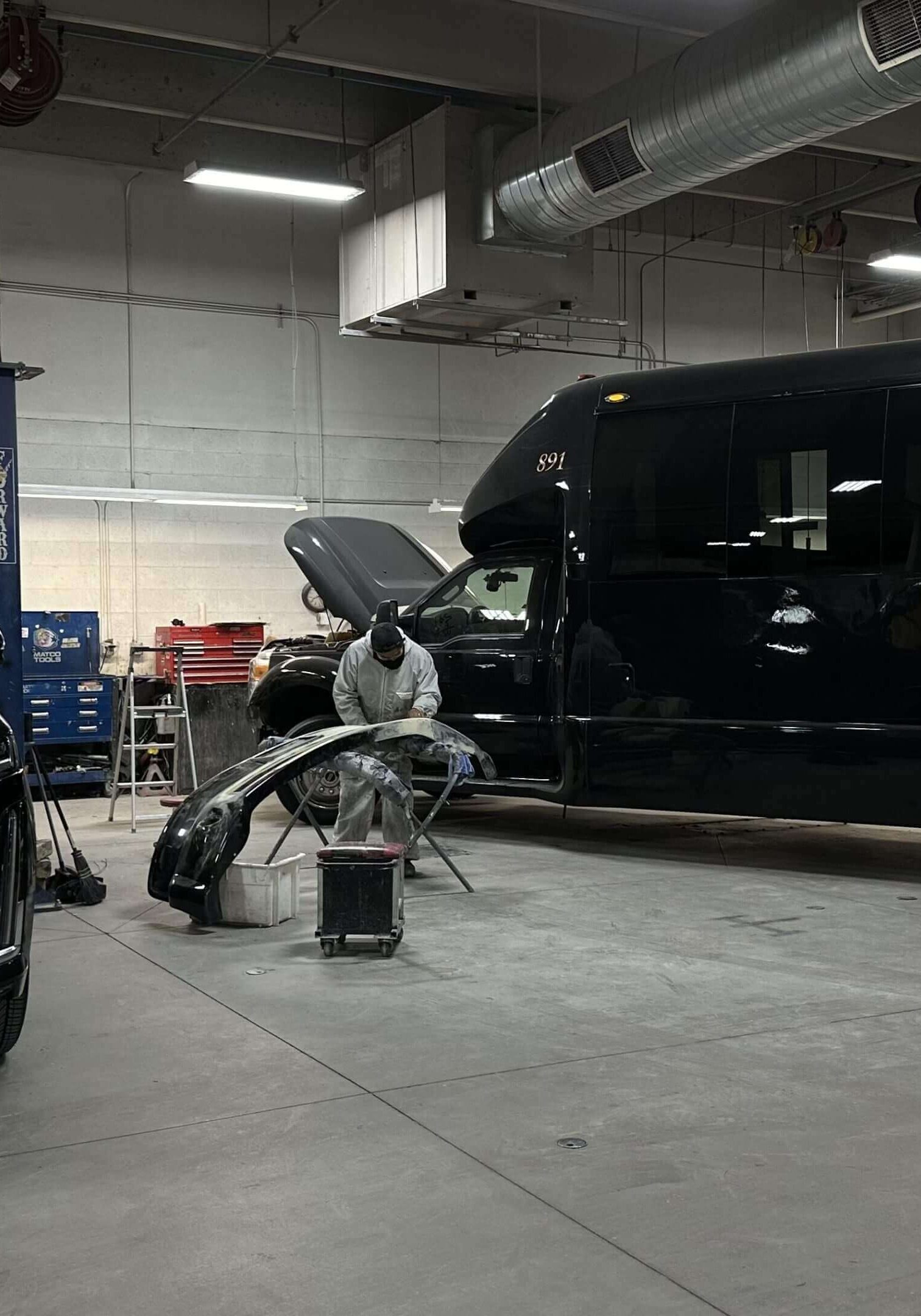 Garage with black SUV and bus.