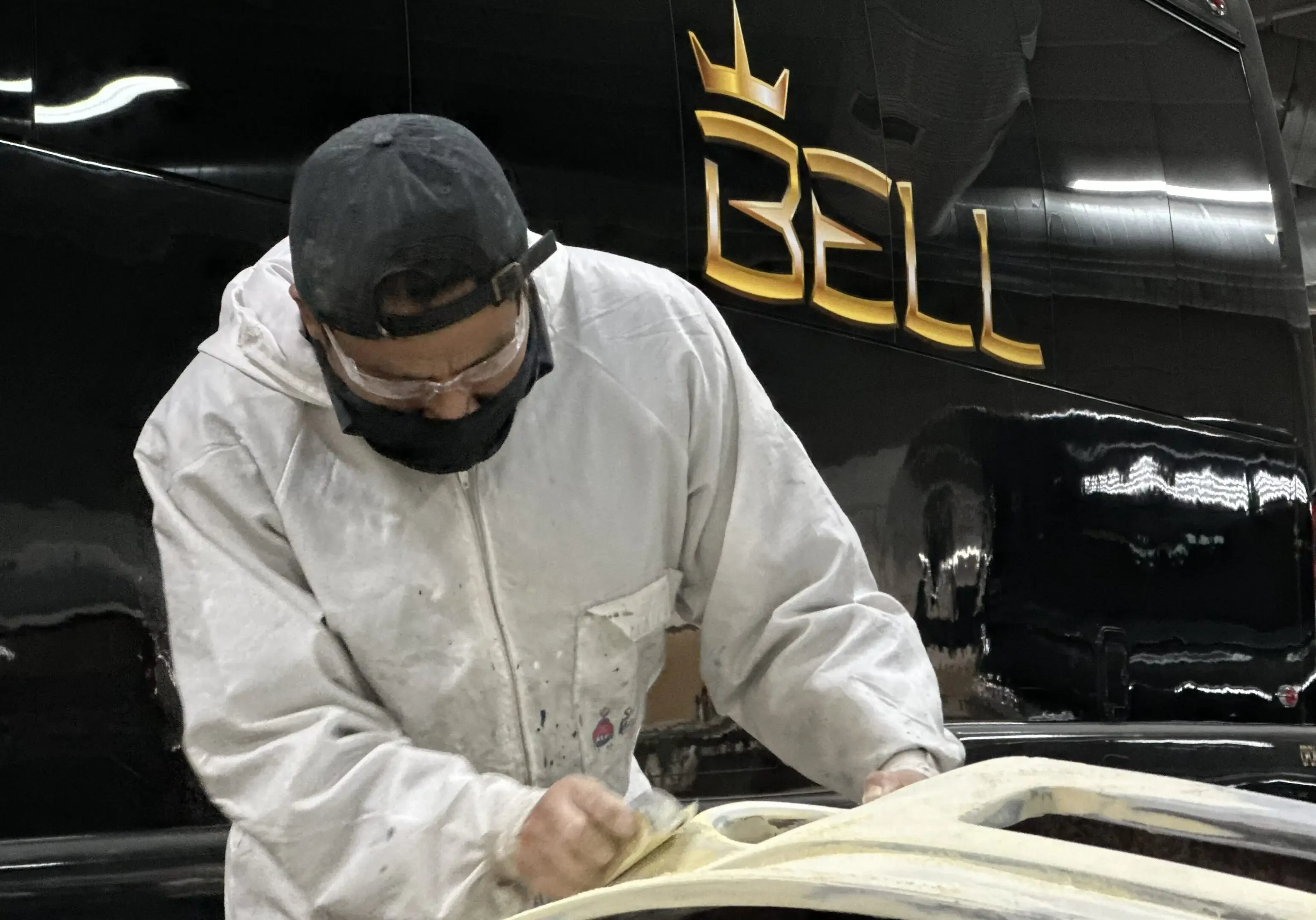 Man sanding vehicle in workshop environment.